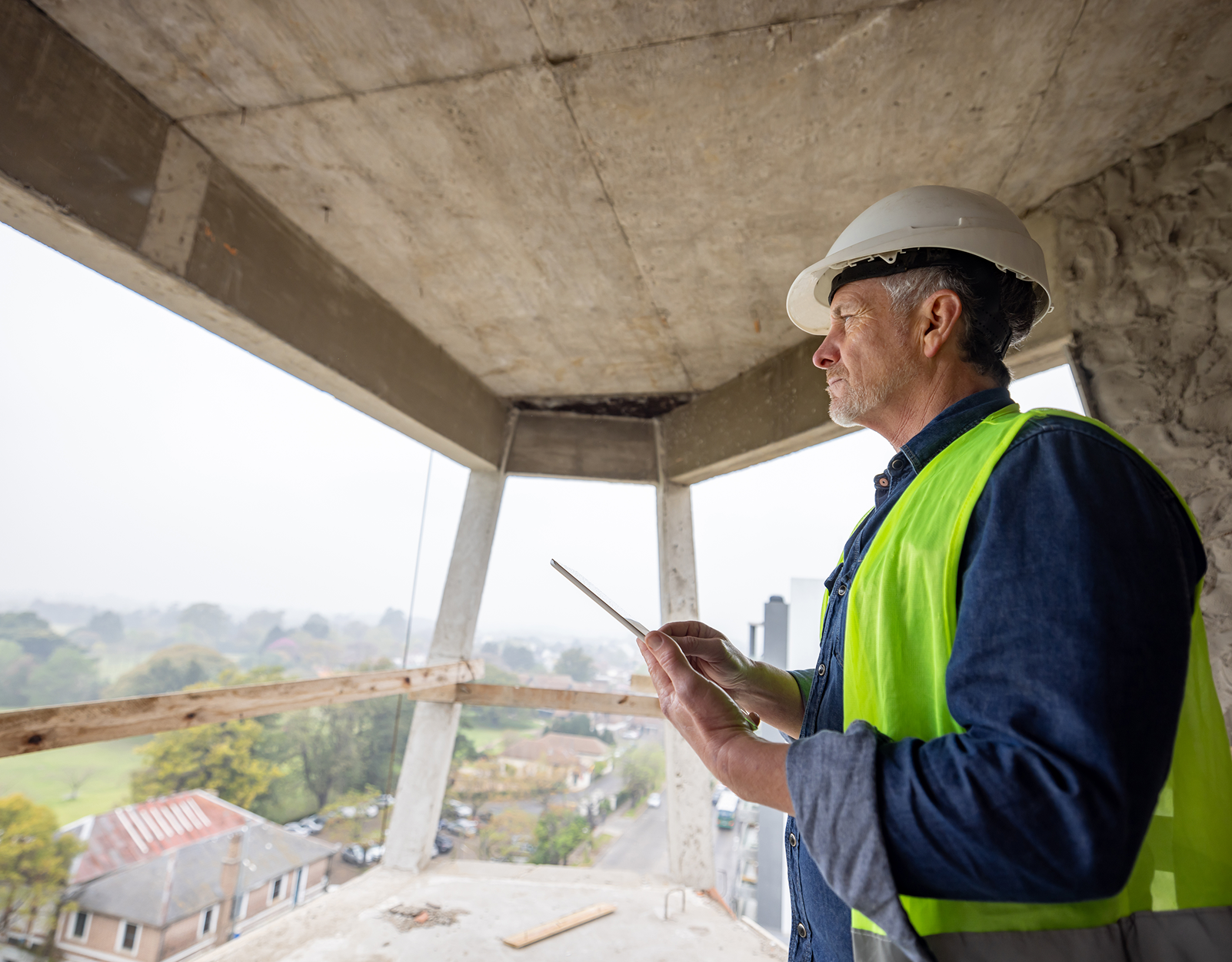 Man in hard hat surveying construction project